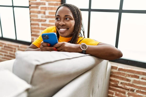 Afroamerykanka Pomocą Smartfona Siedzi Kanapie Domu — Zdjęcie stockowe
