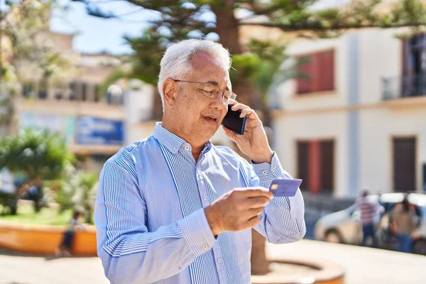 Hombre Mayor Hablando Teléfono Inteligente Utilizando Tarjeta Crédito Parque —  Fotos de Stock