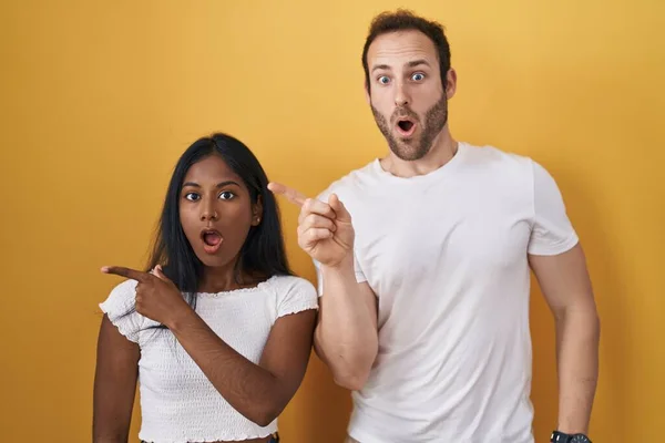 Interracial Couple Standing Yellow Background Surprised Pointing Finger Side Open — 图库照片