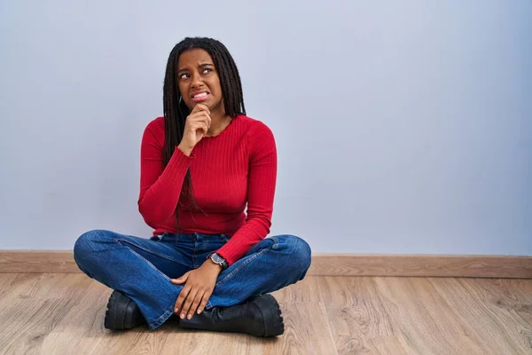 Młody Afroamerykanin Warkoczami Siedzący Podłodze Domu Myślący Pytaniu Zaniepokojony Zdenerwowany — Zdjęcie stockowe
