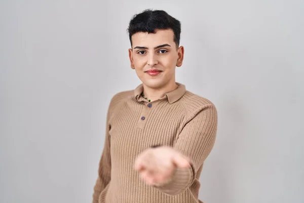 Non binary person standing over isolated background smiling cheerful offering palm hand giving assistance and acceptance.