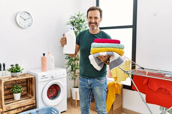 Hombre Hispano Mediana Edad Haciendo Lavandería Sosteniendo Botella Detergente Ropa —  Fotos de Stock