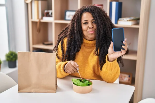 Size Hispanic Woman Eating Take Away Salad Holding Smartphone Smiling — Stok fotoğraf