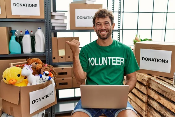 Young Handsome Man Wearing Volunteer Shirt Using Laptop Pointing Back — Stock Photo, Image