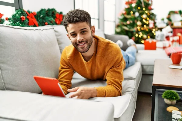 Hombre Árabe Joven Usando Touchpad Acostado Sofá Por Árbol Navidad — Foto de Stock