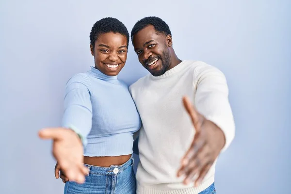 Young African American Couple Standing Blue Background Smiling Friendly Offering — Stock Photo, Image