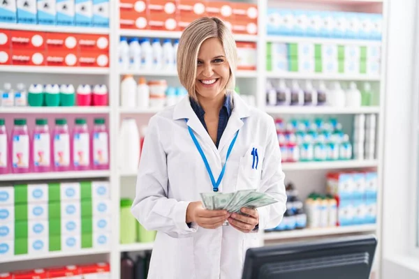Young Blonde Woman Pharmacist Smiling Confident Counting Dollars Pharmacy — Zdjęcie stockowe
