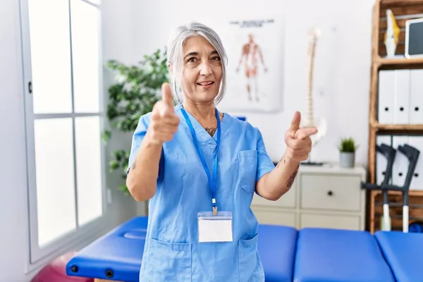 Šedovlasá Žena Středního Věku Uniformě Fyzioterapeutky Lékařské Klinice Ukazuje Prstem — Stock fotografie