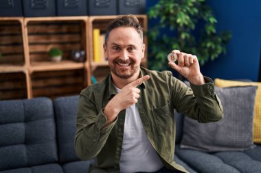 Orta yaşlı, beyaz bir adam elinde sanal para tutuyordu. Bitcoin mutlu bir şekilde el ve parmağıyla işaret ediyordu. 