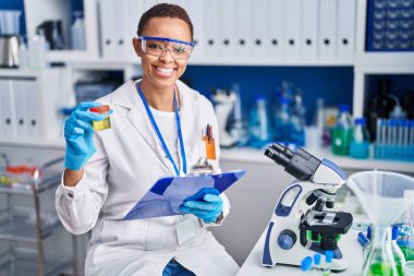 Afrika kökenli Amerikalı kadın bilim adamı elinde idrar tüpü okuma belgesi tutuyor.