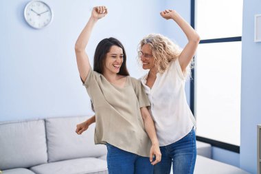 Two women mother and daughter dancing at home