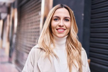 Sokakta kendine güvenen genç sarışın kadın gülümsüyor