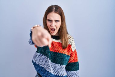 Young hispanic girl standing over blue background pointing displeased and frustrated to the camera, angry and furious with you 