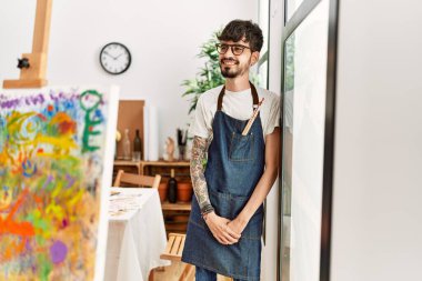 Genç İspanyol ressam mutlu bir şekilde resim stüdyosunda duruyor..