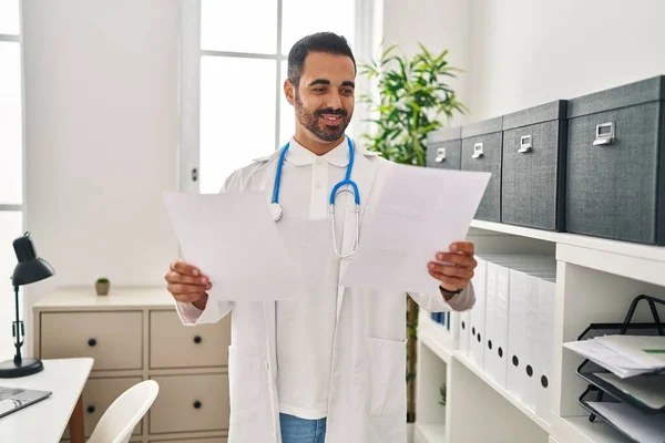Ung Latinamerikan Man Bär Doktor Uniform Läsa Rapport Dokument Kliniken — Stockfoto