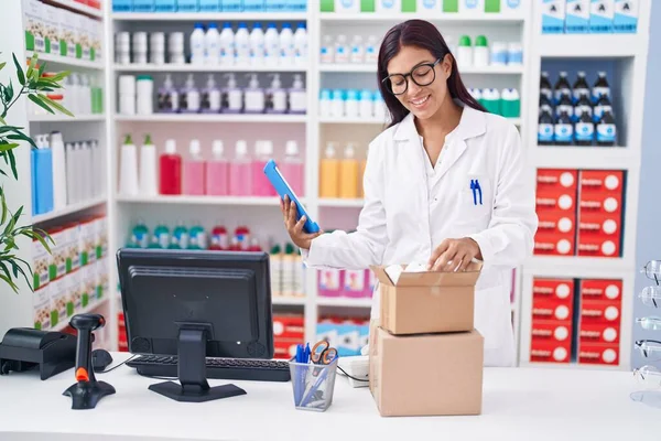 stock image Young beautiful hispanic woman pharmacist using touchpad holding pills bottle at pharmacy