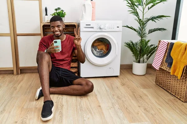 Young African American Man Using Smartphone Waiting Washing Machine Smiling — Zdjęcie stockowe