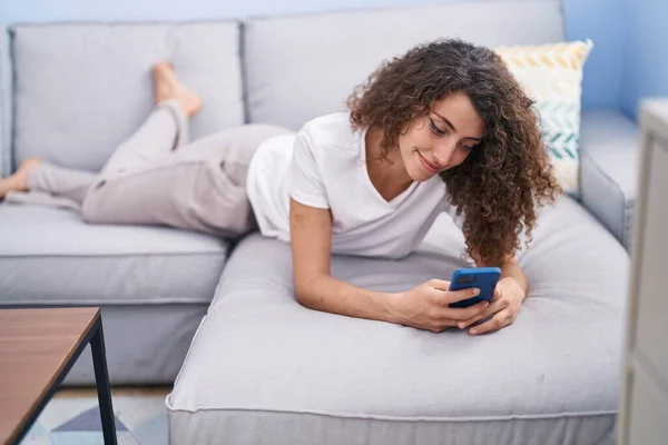 年轻美丽的惊慌失措的女人用智能手机躺在家里的沙发上 — 图库照片