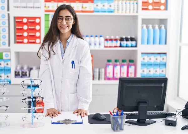 Young Hispanic Girl Pharmacist Writing Report Clipboard Pharmacy — Foto de Stock