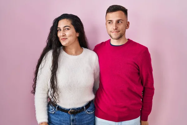 Young Hispanic Couple Standing Pink Background Smiling Looking Side Staring — Stockfoto