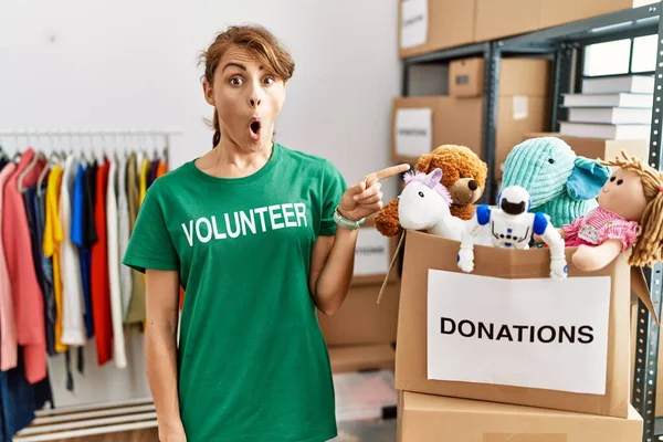 Mulher Branca Bonita Vestindo Shirt Voluntária Doações Stand Surpreso Apontando — Fotografia de Stock
