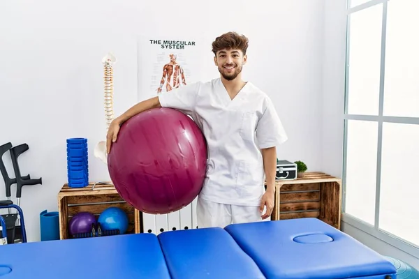 Mladý Arabský Muž Uniformě Fyzioterapeuta Drží Fit Míč Klinice — Stock fotografie
