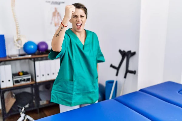 Young Hispanic Woman Wearing Physiotherapist Uniform Standing Clinic Angry Mad — Photo