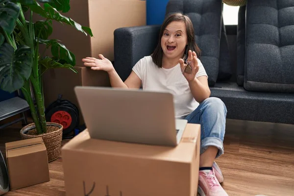 西班牙忧郁症女孩坐在新家的地板上 手持笔记本电脑 带着快乐的笑容和高傲的表情庆祝自己的成就 — 图库照片