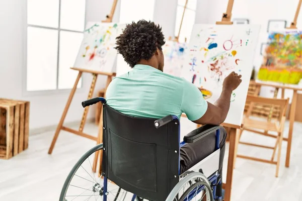 Young african american disabled artist man sitting on wheelchair drawing at art studio.