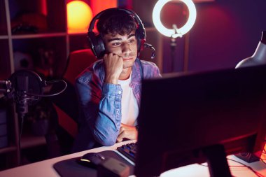 Oyun odasında ciddi bir ifadeyle masada oturan İspanyol asıllı genç adam.