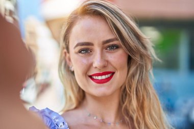 Genç ve güzel İspanyol kadın gülümsüyor. Kendine güvenen. Sokakta kamerayla selfie çekiyor.