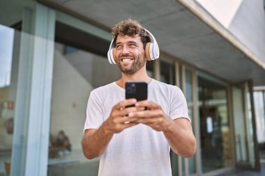 Sokakta müzik dinlerken kendinden emin gülümseyen İspanyol genç adam.