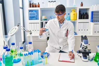 Latin asıllı genç bilim adamı laboratuardaki belgede sıvı yazıyı tartıyor.