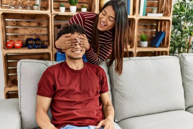 Kadın, erkek arkadaşına sürpriz yapıyor. Elleri ve gözleri evde kanepede oturuyor..