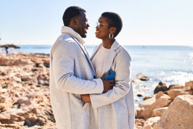 Erkek ve kadın çift sahilde birbirlerine sarılıyorlar.