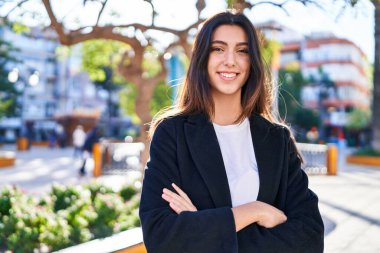 Parkta kollarını kavuşturmuş genç, güzel İspanyol bir kadın.