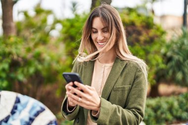 Parkta akıllı telefon kullanan kendine güvenen genç bir kadın.