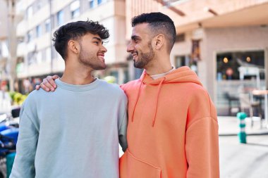 İki erkek caddede birbirlerine sarılıyorlar.