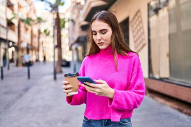 Sokakta kahve içen akıllı telefon kullanan genç bir kadın.