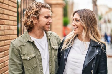 Kadın ve erkek gülümsüyor. Kendilerine güveniyorlar. Sokakta sarılıyorlar.