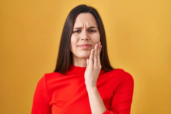 歯痛や歯の病気のために痛みを伴う表現で手で口に触れる黄色の背景に立って若いヒスパニックの女性 歯科医 — ストック写真
