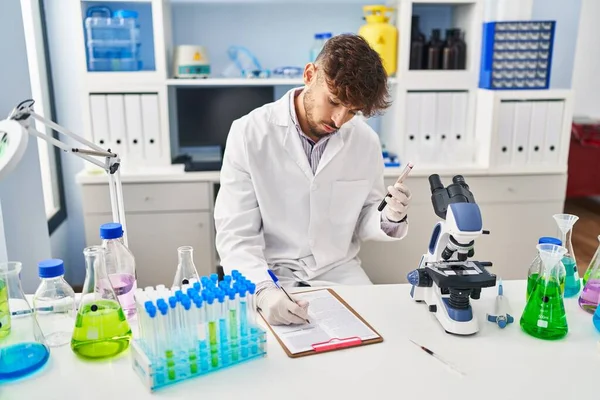 若いアラブ人の男性科学者は 実験室での血液検査管を分析する文書に書きます — ストック写真