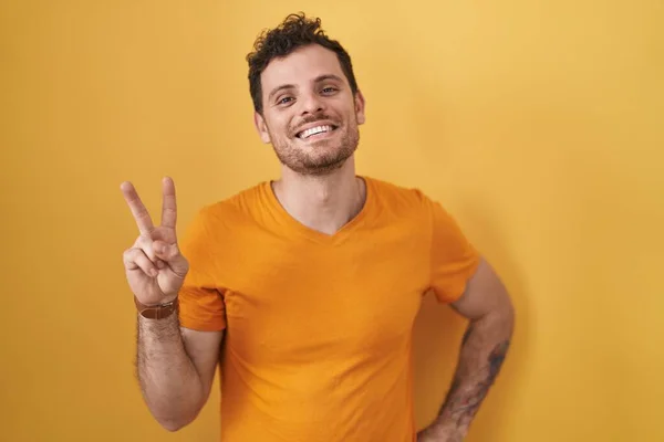 Ung Hispanic Mann Står Gul Bakgrunn Smiler Til Kameraet Med – stockfoto