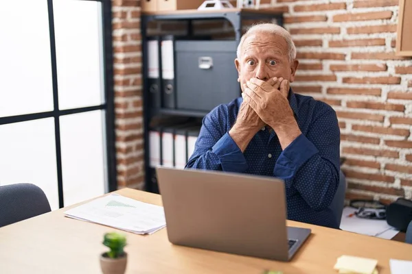オフィスでコンピュータのラップトップを使用して作業灰色の髪のシニア男は間違いのために手で口をカバーショックを受けました 秘密の概念 — ストック写真