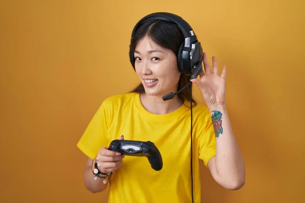 中国年轻女子一边玩电子游戏一边牵着控制器 一边两手空拳地听着谣言或闲话 聋的概念 — 图库照片