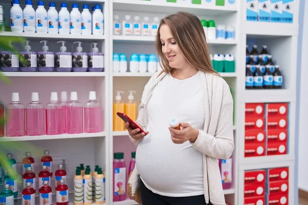 Młoda Kobieta Ciąży Klient Pomocą Smartfona Trzymając Butelkę Tabletek Aptece — Zdjęcie stockowe