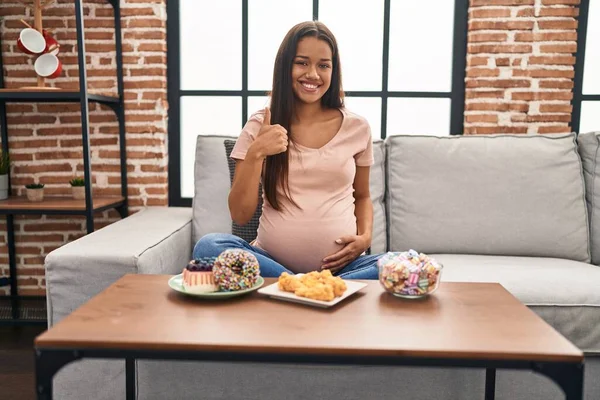 Mujer Embarazada Joven Comiendo Dulces Casa Sonriendo Feliz Positivo Pulgar — Foto de Stock