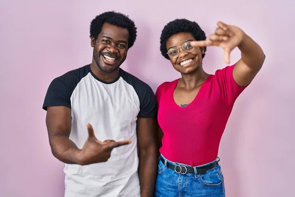 年轻的非洲裔美国夫妇站在粉红的背景上 微笑着 用双手和手指做框架 脸上洋溢着幸福的表情 创意与摄影概念 — 图库照片