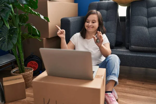 西班牙裔女孩 患有抑郁症 坐在新家的地板上 带着笔记本电脑 微笑着 手指手画脚地指向旁边 — 图库照片