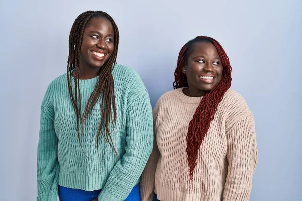 顔に笑みを浮かべて横に見える青い背景の上に立って2人のアフリカの女性は 自然な表現 自信を持って — ストック写真